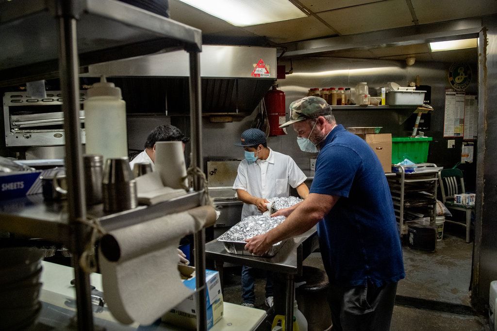 Josh Cohen, owner of Jimmy's Diner, grabs sandwiches to bring outside for Neil Sheehan, co-founder of North Brooklyn Angels. Mr. Sheehan and his partner, John Merz, bring meals to workers at Woodhull Hospital. Photo Credit: Hilary Swift for The New York Times